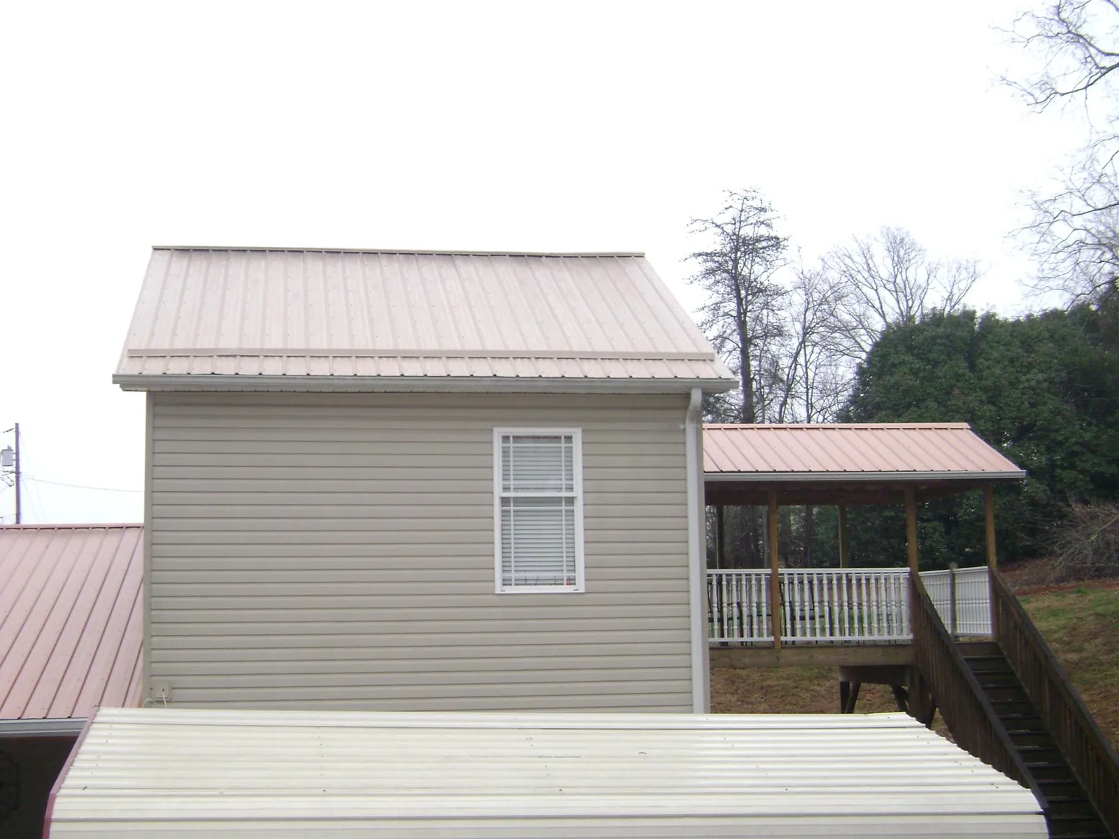 Tan metal roofs on a two story addition and attached porch, from a Roof Replacement job in Meeker
